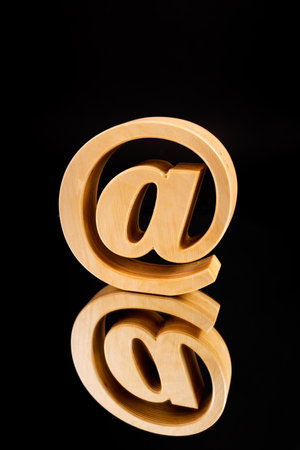 A wooden textured "At" symbol isolated on the  black backgroundの写真素材