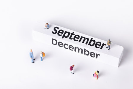 A closeup shot of figurines of students and an instructor standing around a calendarの写真素材