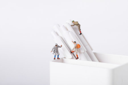A closeup shot of figurines of students climbing on pens in a potの写真素材