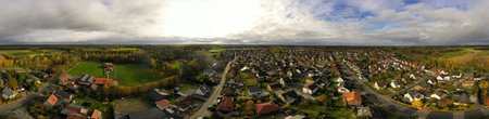 A panoramic shot of houses with a road in a village surrounded by trees in the countrysideの写真素材