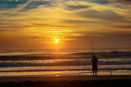 A silhouette of a fisherman on the coast of Guaratuba in Brazil at sunsetの写真素材