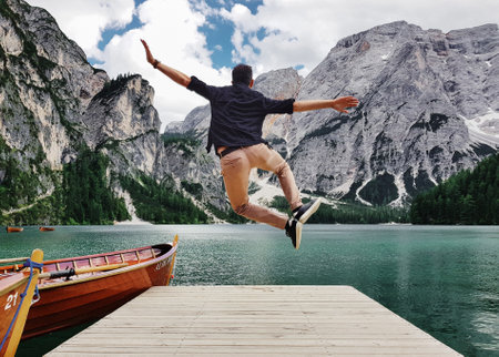 A back view of a man jumping on wooden pier in the Fanes-Sennes-Prags Nature Park in Italyの写真素材