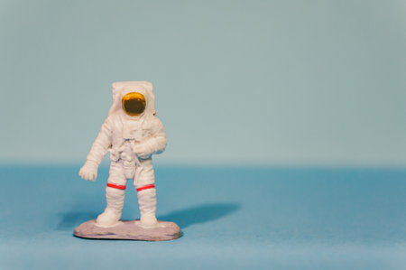 A closeup shot of an astronaut toy with a white spacesuit isolated on a light blue backgroundの写真素材