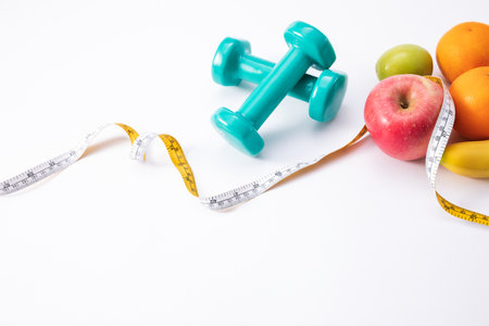 A closeup shot of weights, apples, and measuring tape on a white surface with space for textの写真素材