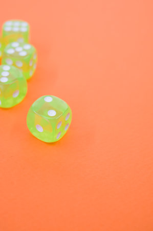 A top view closeup of five neon green dice isolated on an orange backgroundの写真素材