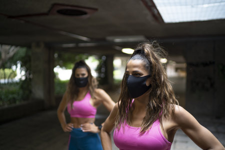 Two Caucasian athletic females running and doing morning workouts with medical masks - the new normal after Covid-19の写真素材