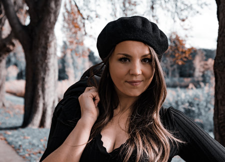 A pretty Caucasian girl wearing autumn clothes and posing in a colorful park