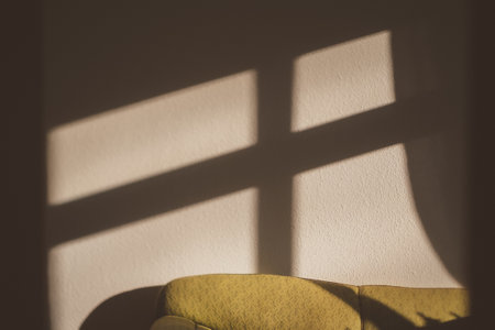A shadow of the window cross on a wall and couchの写真素材