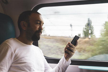 A man on his phone travelling on trainの写真素材