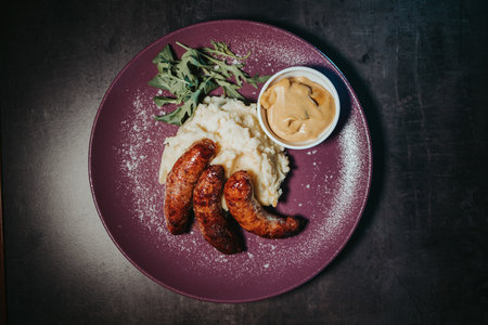 A top view shot of grilled sausages on mashed potato with herbs and sauceの写真素材