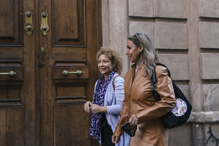 A shallow focus shot of two adult cheerful women walking along the street