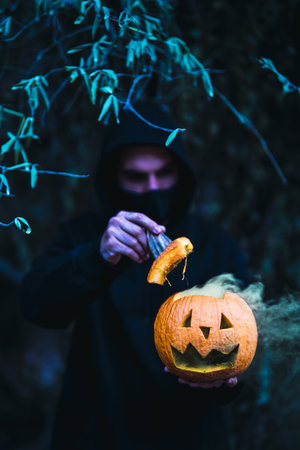 A vertical shot of a man holding a carved pumpkin with yellow smoke - the concept of Halloweenの写真素材