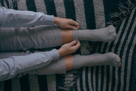 A top view of a young female putting on some socks on a cold day to spend at home. Cozy Home...