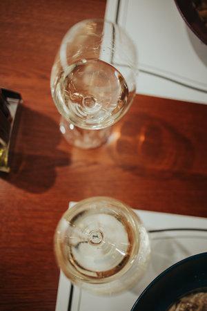 A high angle shot of white wine glasses on a wooden tableの写真素材