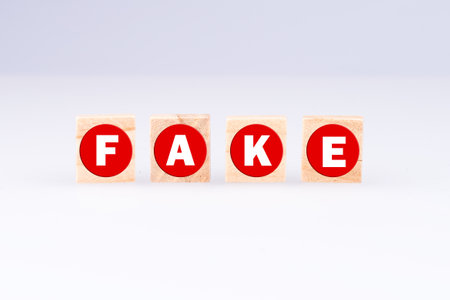 The word 'fake' written on wooden blocks isolated on a gray backgroundの写真素材