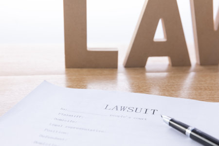 A selective focus shot of a document of the lawsuit and word "Law" from wooden letters on the backgroundの写真素材