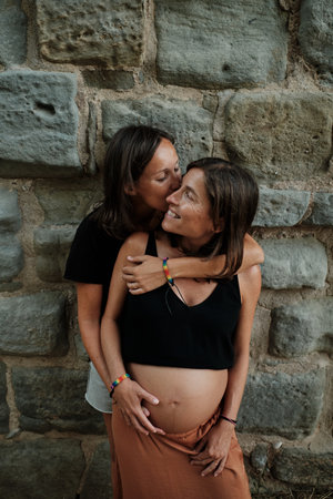 A vertical closeup of a pregnant lesbian couple doing a photoshoot in a parkの写真素材