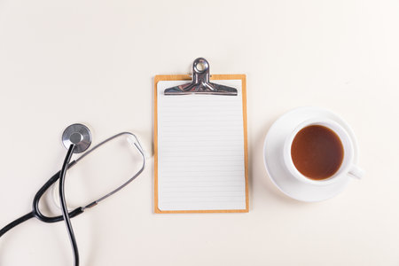 A top view shot of a notepad, medical stethoscope and a cup of a hot tea