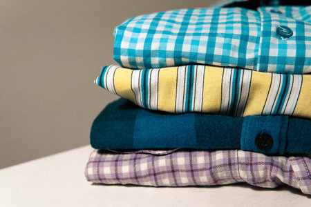 A closeup of folded flannel and striped shirts on the tableの写真素材