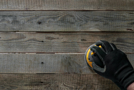 A top view of hand with protective glove holding equipment over a wooden plankの写真素材