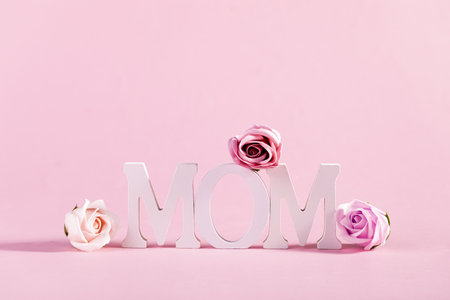 The word "Mom" decorated with flowers on pastel pink backgroundの写真素材