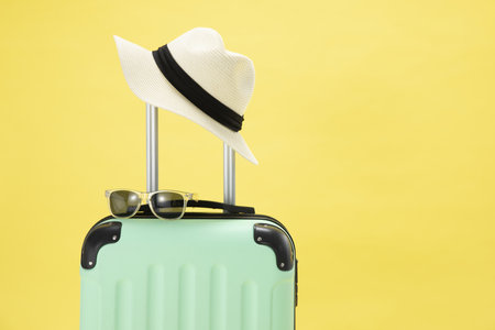 A top view of a suitcase, sunglasses, camera and hat on a yellow background - vacation conceptの写真素材