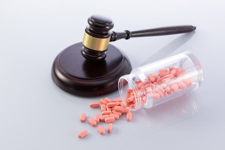 A closeup shot of the judge's gavel and pills falling from a jar - concept of illegal sale of medicinesの写真素材