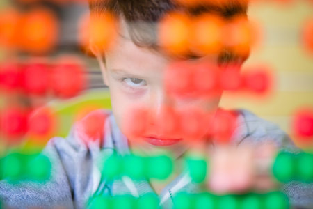 A little Caucasian baby boy looking angry and frustrated while playing with an abacus