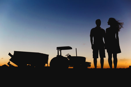 The silhouette of a romantic couple on an industrial farm during sunsetの写真素材