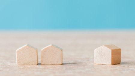 A selective focus of wooden house miniatures on blue backgroundの写真素材