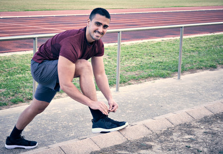 A young man tying sneakers in the sports hall to do athletics. Health and sport concept