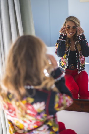 A white Caucasian woman checking herself out in the mirror in the hotel roomの写真素材