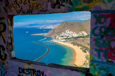 A view of the Teresitas beach through a window with graffiti art on the wallの写真素材
