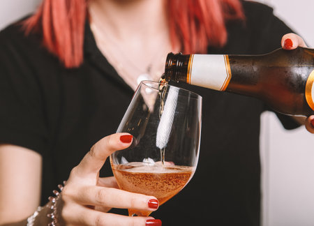 A closeup of a young woman filling a glass of beerの写真素材