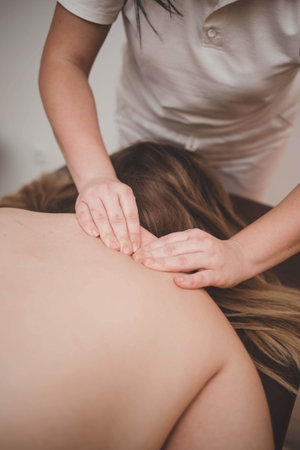 A woman receives a wellness massage of the back, neck, collar areaの写真素材