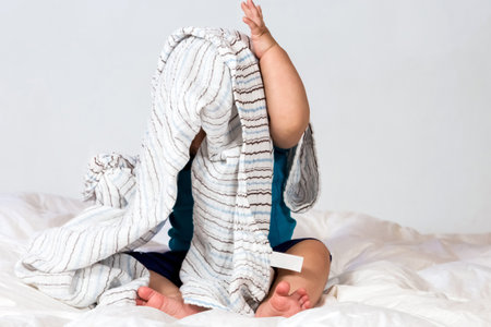 A cute baby covered and hidden under a blanketの写真素材