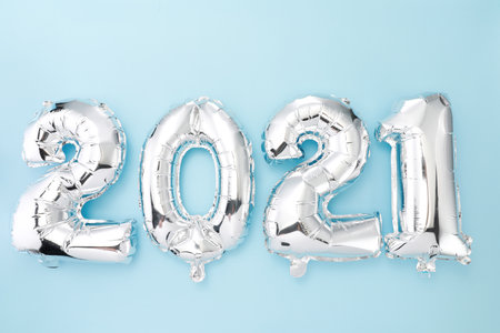 '2021' made with silver balloon numbers on a blue background.の写真素材