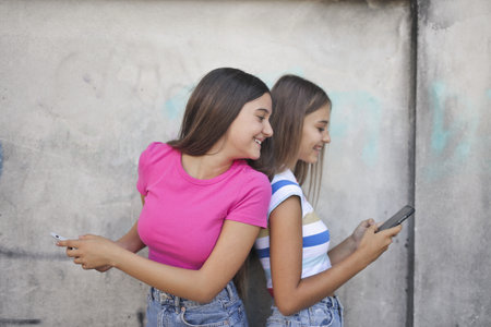 A view of two Caucasian young girls texting with smartphoneの写真素材