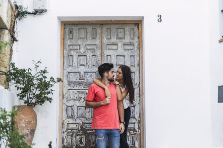 An affectionate couple standing by a decorated wallの写真素材