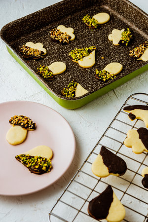 A vertical closeup of cookies on a plate, a pan, and a metallic bar