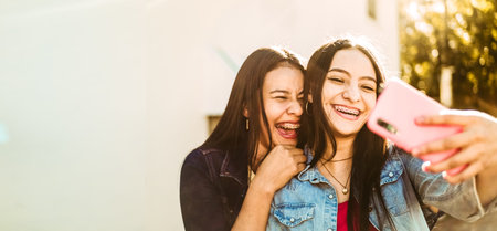 A selective focus shot of cheerful smiling young ladies taking a selfieの写真素材