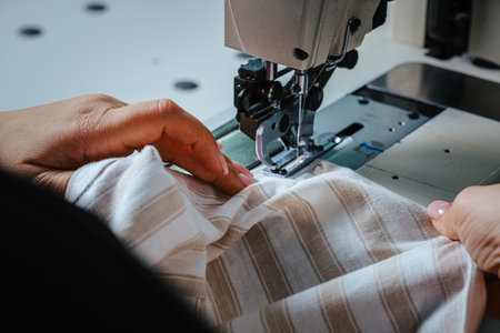 A closeup shot of seamstress hands working on sewing machine