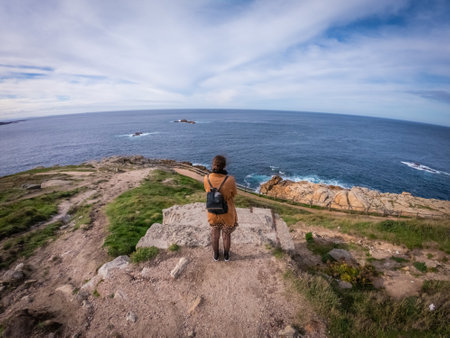 A high angle shot of a stylish female standing and looking at the calm sea near Coruna, Spainの写真素材