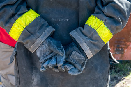A closeup shot of a firefighter with dirty gloves on his backの写真素材