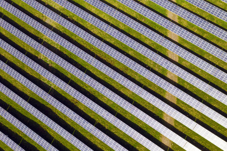 An aerial view of solar panels on the green field in a rural areaの写真素材
