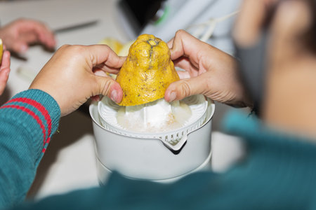 A closeup shot of a person squeezing lemon juice in the kitchen