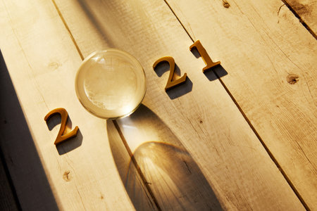 Happy New Year 2021 Golden numbers 2021 with a crystal ball under the sunlight on a wooden backgroundの写真素材