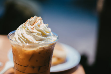 A closeup shot of a cup of espresso with whipped cream and a pie in a plateの写真素材