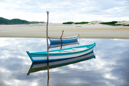 A beautiful view of wooden boats with their reflection on the water in Guarda do Embau, Brazilの写真素材