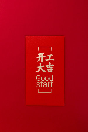 A top view shot of a red envelope with Chinese inscriptions and "Good start" writing isolated on a red backgroundの写真素材